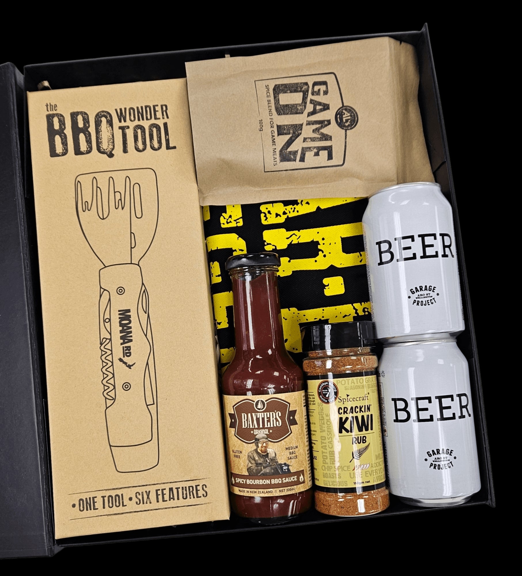 A beautifully curated BBQ gift box with essentials for grilling, including beer, apron, spice mix, sauce, and grilling tool.
