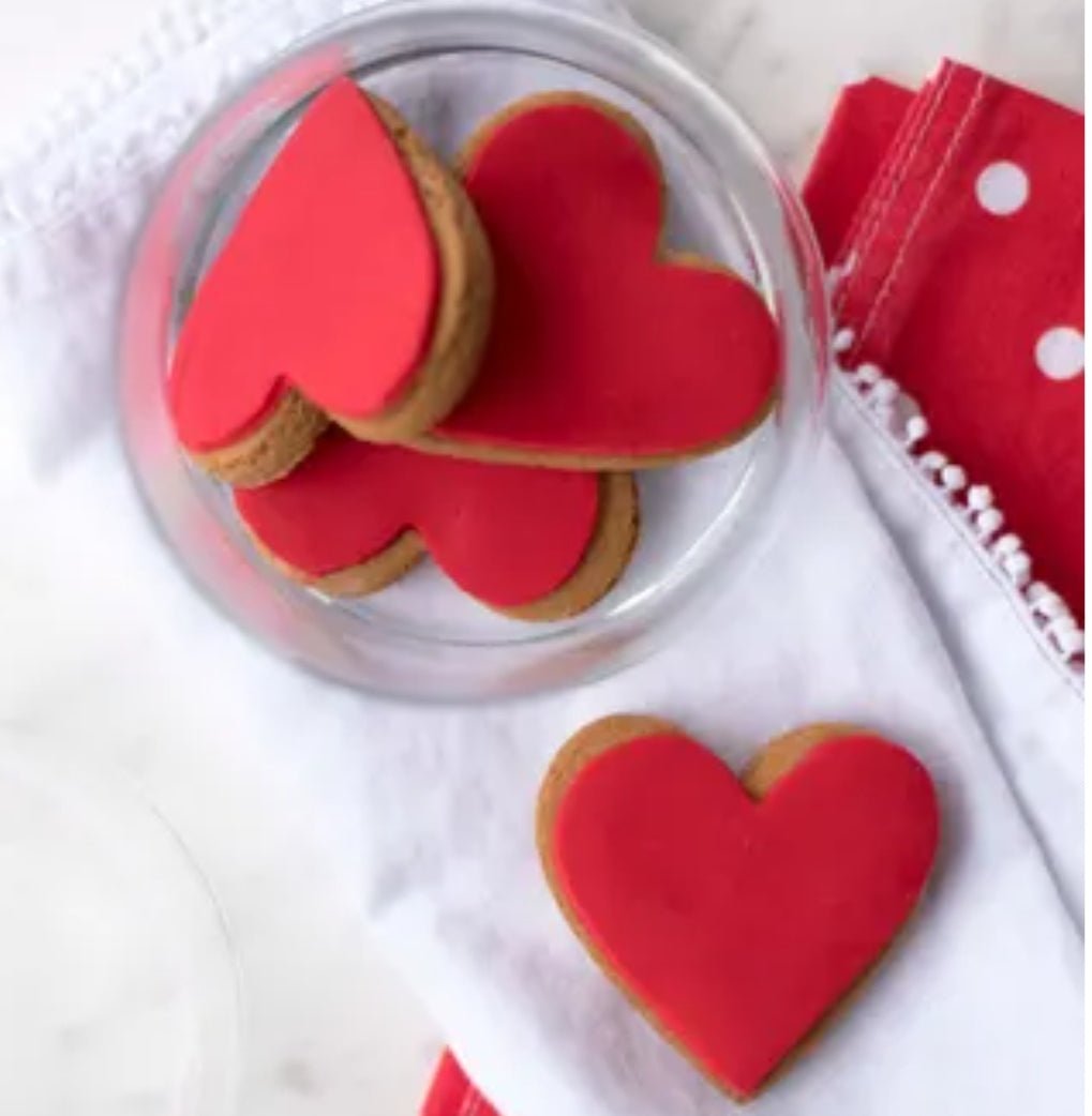 Heart-shaped ginger cookies with vibrant red icing, perfect for gifting on special occasions.