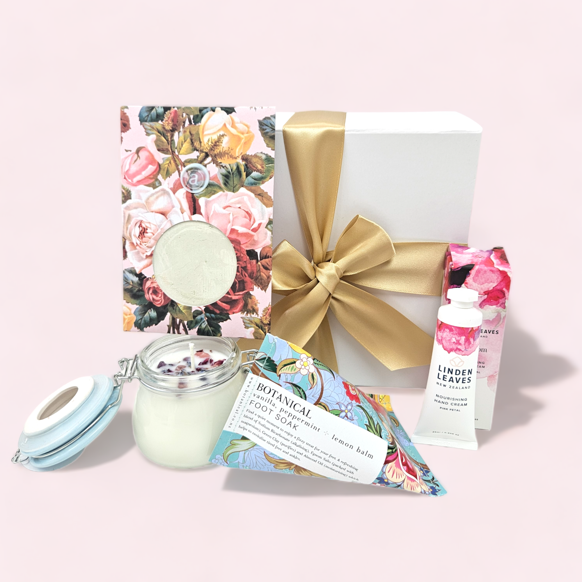 Elegant pink gift box featuring aromatherapy candle, hand cream, facial mask, and foot soak for ultimate relaxation.