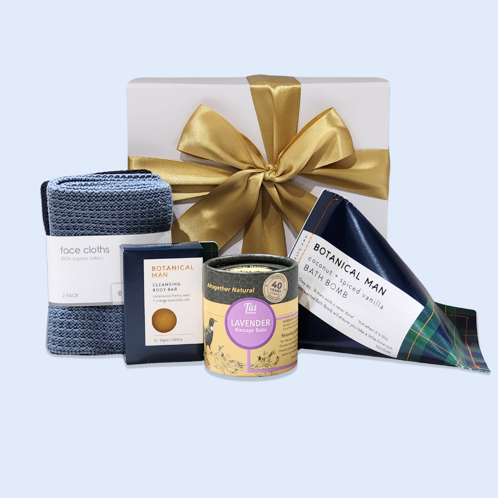 Luxurious gift box for men featuring wellness products like massage balm, cleansing bar, bath bomb, and soft facecloths.