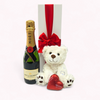 Elegant gift box featuring Moët champagne, chocolate heart, teddy bear, and ribbon for special celebrations.