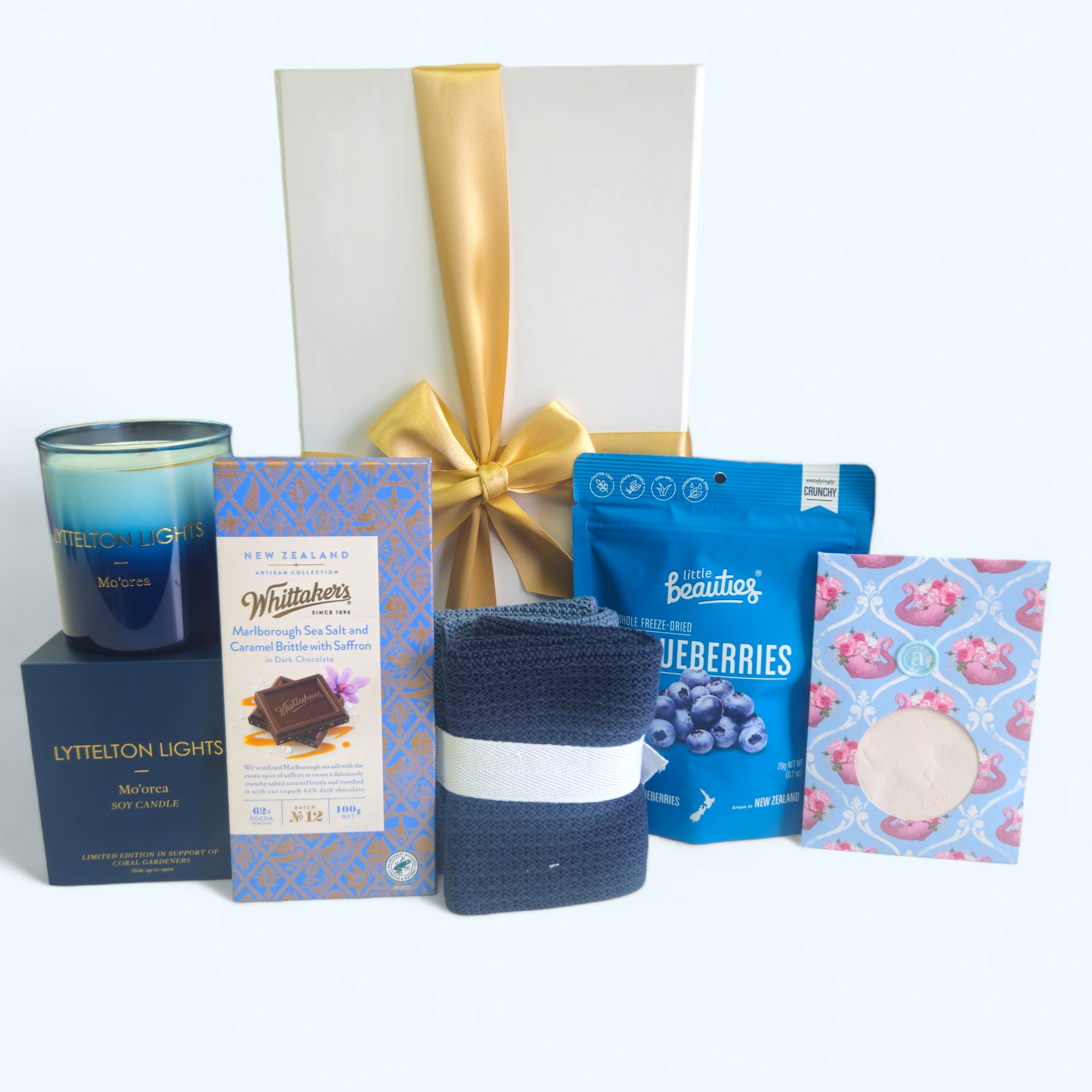 Luxurious 'Shades Of Blue' gift box featuring calming items including a candle, facial mask, facecloths, blueberries, and gourmet chocolate.