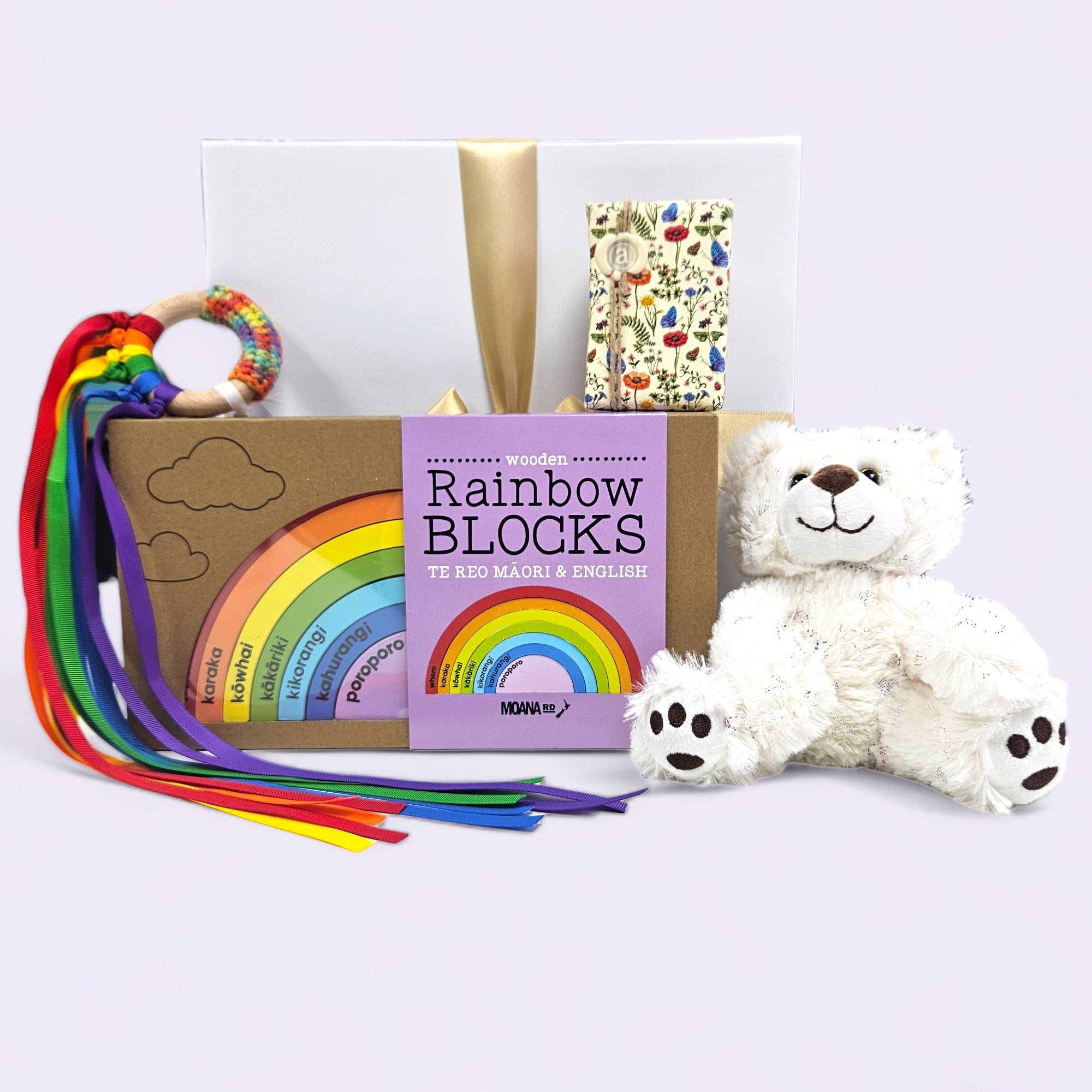 Gift box for newborns featuring a teddy bear, teething toy, rainbow blocks, and gentle soap, beautifully packaged.