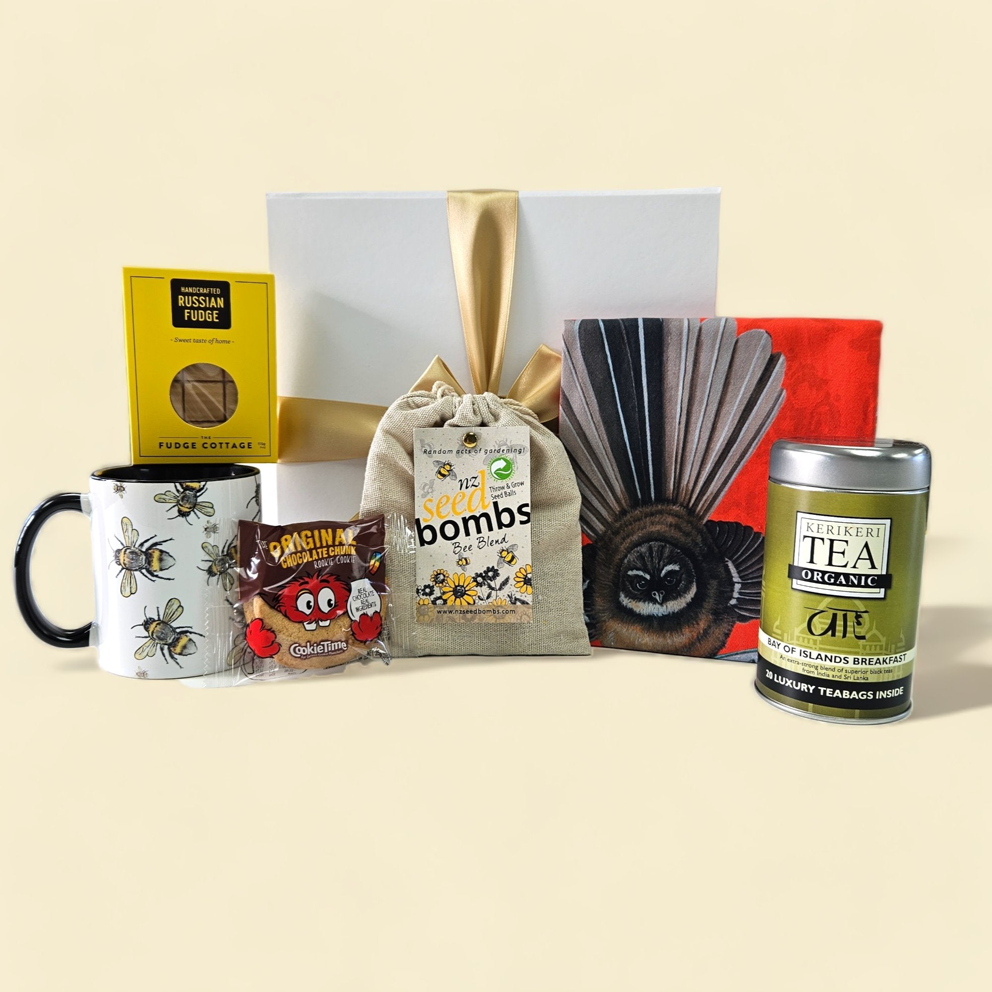 A charming gift box for gardeners, featuring tea, seed bombs, a bee mug, a tea towel, fudge, and a cookie, elegantly packaged.