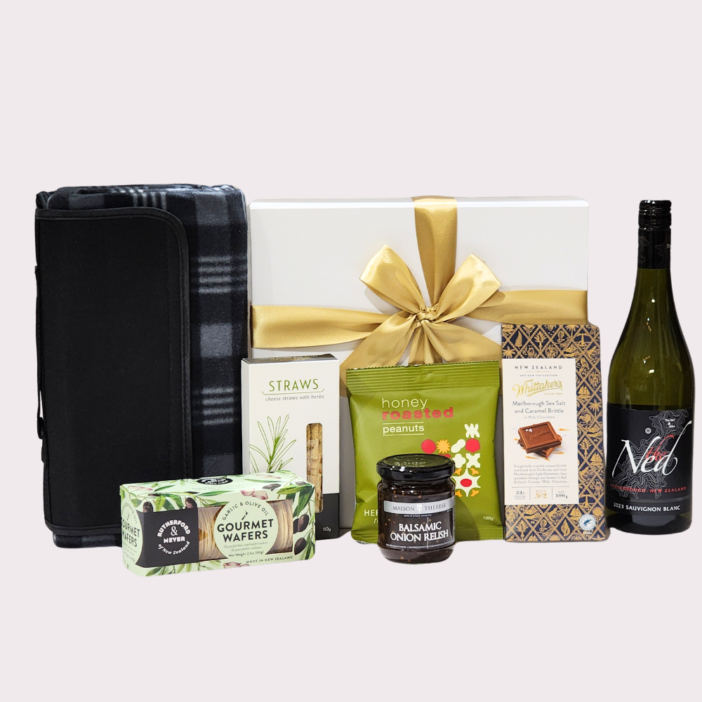 Elegant picnic gift box featuring wine, gourmet snacks, a blanket, and chocolate for memorable outdoor dining.