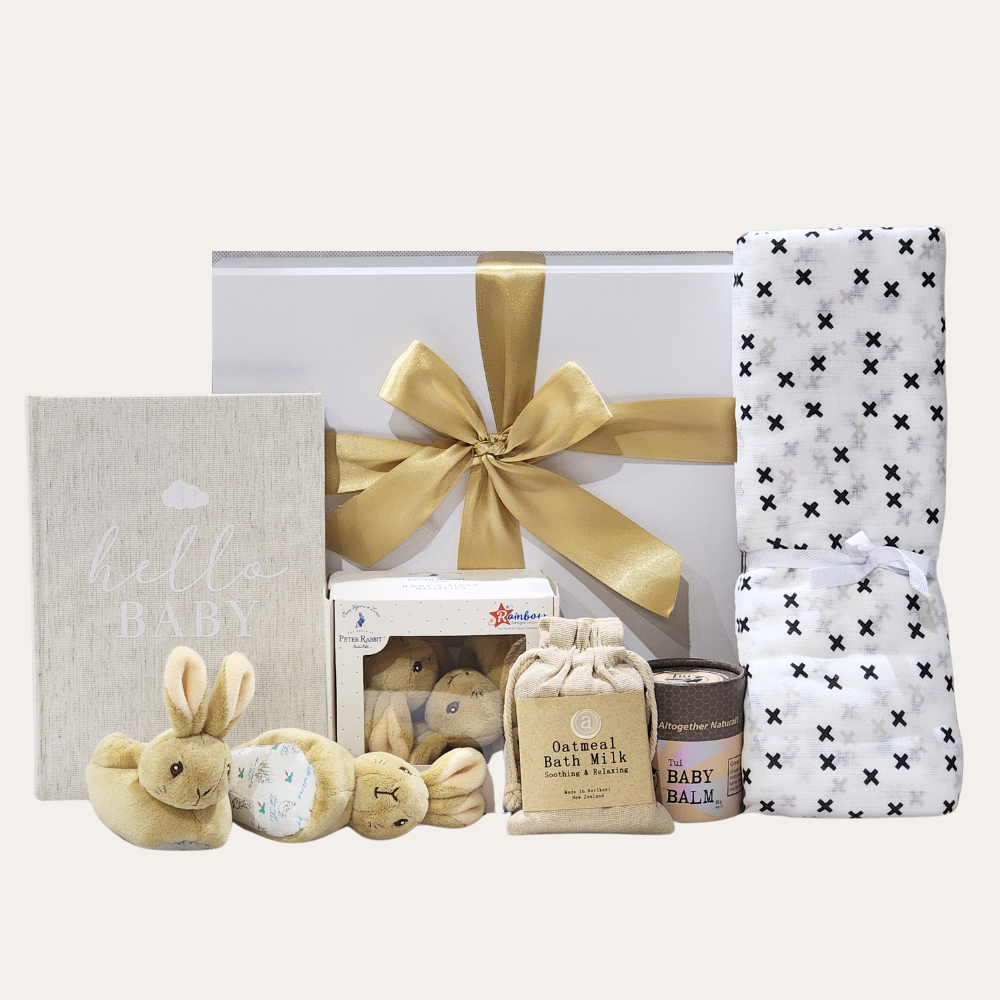 Tiny Treasures Baby Gift Box featuring essentials for newborns, including a journal, booties, balm, blanket, and bath milk.